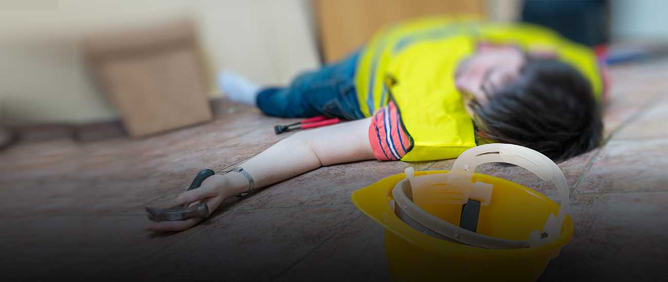 Injured construction worker on the ground with a yellow hard hat nearby.